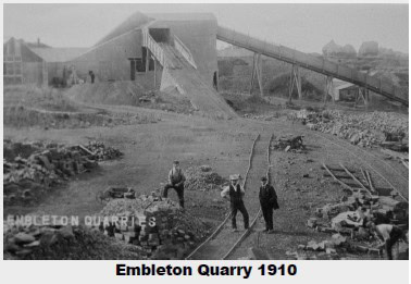Black and white photo of Embleton Quarry in 1910, with three men standing by tracks and quarry buildings.